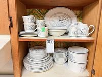 Shelved collection showing plates, bowls, cups, platter, creamer, sugar bowl and ramekins