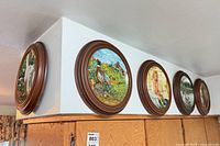 Five framed plates hung on wall showing variety of scenes