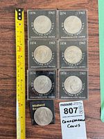 Six Churchill coins in square display holders alongside ruler and lot tag