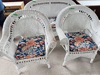 Two white wicker armchairs with navy floral cushions