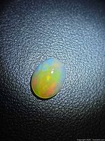 Top view of oval cabochon opal showing play of colour