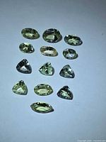 Group of 13 lemon-lime tanzanite gemstones in mixed cuts on white background