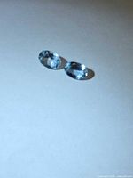 Two oval blue gemstones on neutral background