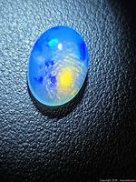 Top view of oval jelly opal showing blue body tone and yellow play of color
