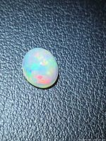 Front view of oval cabochon opal displaying multicolour fire