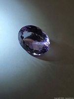 Oval cut purple gemstone side view under spotlight