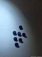 Seven round blue sapphires on light background