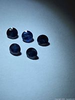 Five round deep blue sapphires viewed top-down under spotlight