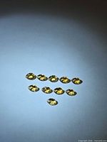 Ten pear-cut citrines arranged on flat surface under spotlight