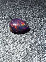 Top view of pear cabochon showing play-of-color on dark background