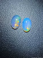 Pair of oval opals showing play of color on textured background