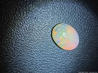 Top view of oval opal cabochon on textured background