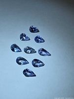 group of nine pear-cut tanzanite stones on white background