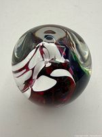 Overall view of spherical art glass paperweight showing internal ribbon design and controlled bubble