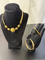 Necklace on display bust; two bracelets on glove display