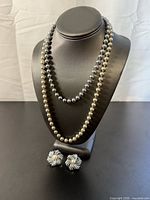 Earrings displayed below two bead necklaces on bust