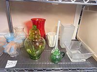 Group of nine glass decorative pieces on shelf