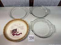 Overview showing three clear glass pie plates and one cream ceramic pie plate
