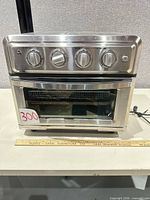 Front view of Cuisinart TOA-60 air fryer toaster oven with ruler for scale and power cord