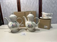 Full lot showing coffee server with lid, second coffee server image repetition, gravy boat on underplate, boxes behind