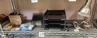Shelf view showing letter trays, file sorter, casters in box, lamp, stapler, assorted fasteners with lot tag