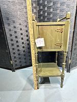 Front view of olive green wooden smoking stand with yardstick for scale