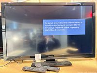 Front view of Panasonic 42-inch TV with remotes and on-screen no-signal message