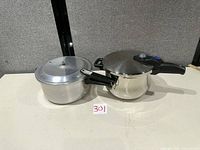 Aluminum and stainless pressure cookers side by side with lids on