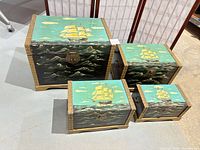 Four nesting nautical trunks closed, showing size gradation and painted ship scenes