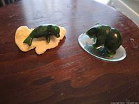 Front view of both jade figurines showing bear on glass base and seal on white stone base