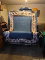 Full view of rug showing blue centre, floral border, and fringe