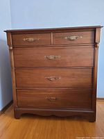Front view of walnut chest showing five drawers and hardware