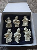Six porcelain cherub figurines in lined box