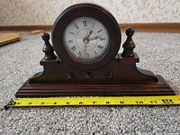 Front of wooden mantel clock with tape measure for width