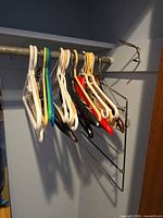 Assortment of plastic coat hangers and one metal multi-bar trouser hanger on closet rod