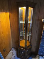 Full view of curio cabinet showing glass panels, shelves, and lighting