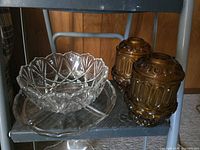 Clear cut glass bowl, clear plate beneath, two amber pressed glass candle holders