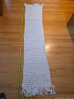 Full length view of crocheted scarf with measuring tape showing length