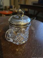 Jar assembled showing glass body, handle, silver-plated rim, hinged lid with finial and spoon installed