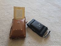 Camera, leather case, manual displayed on floor