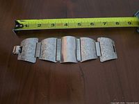 Full bracelet laid flat beside tape measure showing length