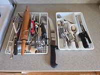 Overall view showing all utensils in dish rack, flatware in drawer tray and chef’s knife on counter