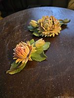 Two porcelain flower sculptures on table showing color and form
