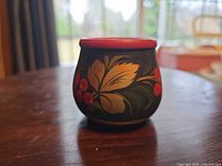 Front view of wooden bowl showing painted leaves and berries