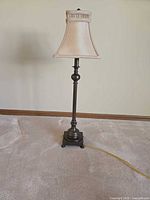 Full frontal view of bronze candlestick lamp with shade
