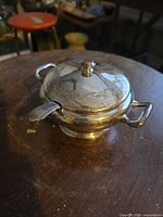 lidded silver-plated soup tureen with ladle inserted through notch
