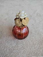 Front view showing red glass body, gold collar and ivory rose finial