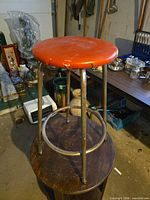 Overall view of vintage metal stool with red vinyl seat