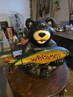 Front view of bear statue holding welcome fish