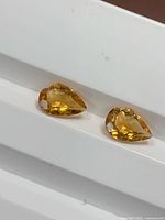 Pair of pear-cut citrines on white background showing overall shape and color